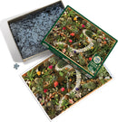 Cobble Hill Jigsaw Puzzle titled 'Succulent Garden'. The image shows a colorful arrangement of various succulents, cacti, and pebbles, showcasing vibrant greens and pops of pink, red, and orange flowers. The puzzle pieces are scattered within an open box, with the puzzle layout visible beside it, depicting the lush garden scene.
