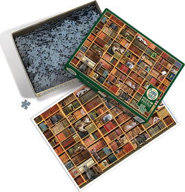 The Cat Library jigsaw puzzle by Cobble Hill, featuring a detailed image of a bookshelf filled with colorful books and playful cats. The puzzle box is open, with pieces scattered and a visual reference of the completed puzzle beside it.