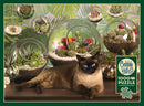 A cozy terrarium-themed jigsaw puzzle featuring a Siamese cat lounging on a wooden surface near various glass terrariums filled with succulent plants and colorful cactus flowers. The background is adorned with lush green tropical leaves. The puzzle contains 1000 pieces and includes a poster.