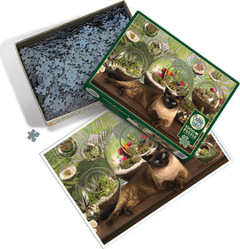 The Cobble Hill Terrarium Cat jigsaw puzzle features a serene indoor scene with a cat lounging in front of beautifully arranged terrariums filled with vibrant plants. The puzzle box is open, showing numerous blue jigsaw pieces and the colorful image on the lid, which depicts the cozy setting. The captivating visuals invite puzzle enthusiasts to enjoy a relaxing and engaging experience.