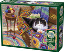 Comfy Cat jigsaw puzzle by Cobble Hill features a cozy scene with a fluffy black and white cat lounging on a colorful, crocheted blanket surrounded by vibrant yarn balls. The puzzle comes with 1000 pieces and includes a poster for reference.