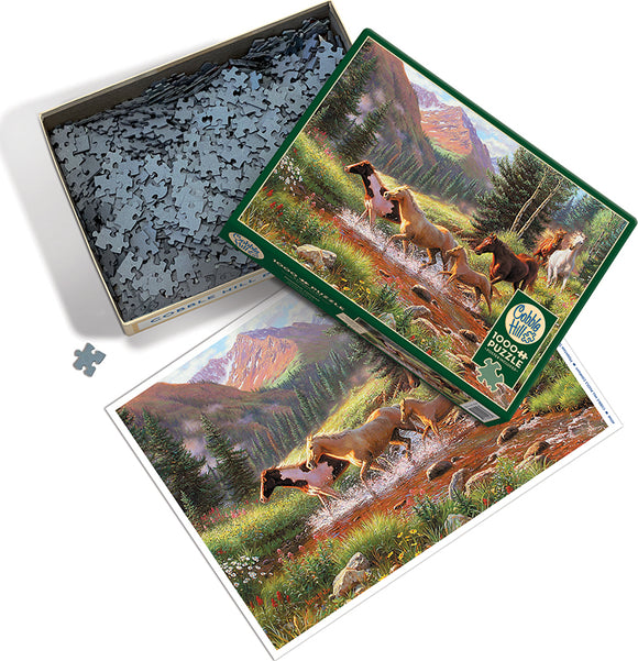 Cobble Hill jigsaw puzzle titled 'Mountain Thunder' featuring a scenic depiction of horses running through a beautiful landscape surrounded by mountains and greenery. The box is partially open with pieces visible inside.