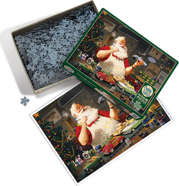 A jigsaw puzzle titled 'Santa Painting Cars' by Cobble Hill. The image depicts Santa Claus in his workshop, surrounded by various toy cars, colorful decorations, and a Christmas tree. The puzzle pieces are shown in an open box beside the puzzle. The vibrant colors and festive theme create a joyful holiday atmosphere.