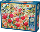The box of the Cobble Hill jigsaw puzzle titled 'Shooting the Breeze'. The design features vibrant flowers, butterflies, and two colorful birds amidst a backdrop of florals. The box is turquoise with intricate illustrations, showcasing the beauty of nature in a whimsical style. A note indicates that the puzzle contains 500+ pieces and includes a poster.