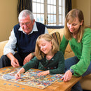 A family enjoying a jigsaw puzzle titled 'Cats and Dogs Museum' by Cobble Hill. A grandfather, daughter, and mother are engaged in assembling colorful pieces together on a wooden table in a cozy living room.