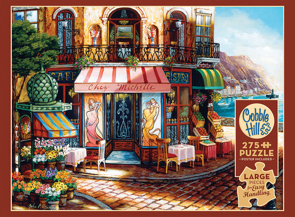 A vibrant jigsaw puzzle titled 'Chez Michelle' by Cobble Hill, featuring a picturesque café scene with a bistro and flower stalls, set in a charming coastal town. The puzzle has 275 large pieces, designed for easy handling, showcasing rich colors and intricate details.