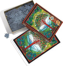 Tree of Life stained glass jigsaw puzzle by Cobble Hill, featuring a vibrant design of a tree with colorful leaves and fruits, set against a scenic background. The box is partially open, exposing the intricate puzzle pieces inside, with an image of the completed puzzle on the side.