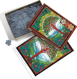 Tree of Life stained glass jigsaw puzzle by Cobble Hill, featuring a vibrant design of a tree with colorful leaves and fruits, set against a scenic background. The box is partially open, exposing the intricate puzzle pieces inside, with an image of the completed puzzle on the side.