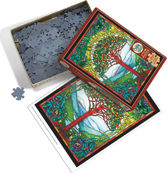 Tree of Life stained glass jigsaw puzzle by Cobble Hill, featuring a vibrant design of a tree with colorful leaves and fruits, set against a scenic background. The box is partially open, exposing the intricate puzzle pieces inside, with an image of the completed puzzle on the side.