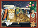 A jigsaw puzzle featuring a serene orange tabby cat lounging on a wooden desk surrounded by colorful books and a vase of tulips. The cat has a content expression, with its eyes half-closed, and is positioned in front of various titles related to cats and fishing, alongside a blue cup and a notepad. The intricate background displays floral patterns.