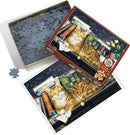 A Cobble Hill jigsaw puzzle featuring a relaxed orange tabby cat lounging atop a stack of colorful books, surrounded by a background of flowers and a patterned wall. The puzzle box is shown next to an unassembled piece, highlighting the intricate design and cozy ambiance.