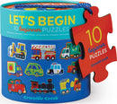 A colorful cylindrical container labeled 'Let's Begin 10 Beginner Puzzles' featuring illustrations of various vehicles including trucks, buses, and construction vehicles. The lid has a blue rope handle, and a red puzzle piece tag shows '10 beginner puzzles' with the brand name 'Crocodile Creek'.