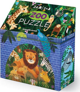Crocodile Creek Puzzle Zoo jigsaw puzzle with 24 colorful pieces featuring a lion and its cubs, surrounded by tropical foliage and various animals. The box showcases whimsical illustrations of a giraffe, peacock, monkey, and more, appealing to young children aged 3 and up.
