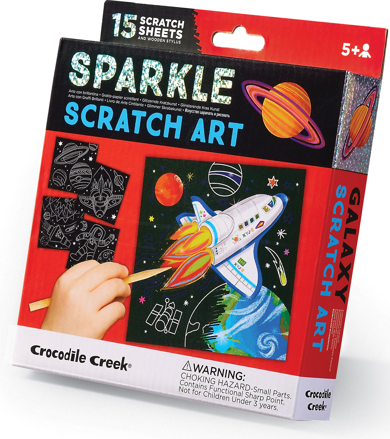 Crocodile Creek Sparkle Scratch Art Space Expl kit featuring 15 scratch sheets and a wooden stylus. The design showcases a colorful rocket ship launching into a starry galaxy filled with planets, stars, and a vibrant backdrop. Recommended for ages 5 and up.