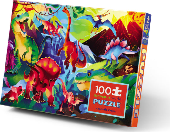 A colorful box of the Dinosaur World Holographic Foil Puzzle by Crocodile Creek features vibrant illustrations of various dinosaurs, including T. rex, Triceratops, and Stegosaurus, set against a lush, prehistoric landscape. The puzzle contains 100 pieces and is designed for engaging play.