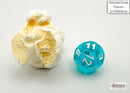 Trans Mini teal and white 7 polyhedral dice by Chessex placed next to a piece of popcorn for scale. The dice features clear teal material with white numerals, ideal for tabletop games.