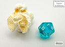 A teal and white polyhedral gaming die by Chessex, displayed next to a piece of popcorn for scale. The die features clear numbers and is designed for tabletop games.
