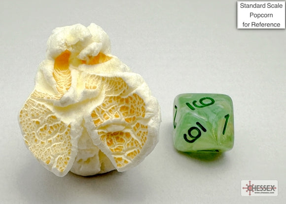 A close-up of a green and dark green marble polyhedral die next to a whimsical popcorn sculpture for scale reference. The die features clearly marked numbers and a unique marbling effect, perfect for tabletop gaming.