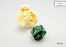 Scarab Mini in jade and gold colors, a polyhedron-shaped gaming die by Chessex. The die is shown next to a piece of popcorn for scale, highlighting its intricate design and vibrant colors.
