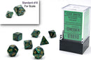 Chessex Scarab Mini polyhedral dice set in jade and gold. The set includes seven dice arranged artfully, with a standard d10 visible for scale. The packaging is clear, showing the brand and product details.