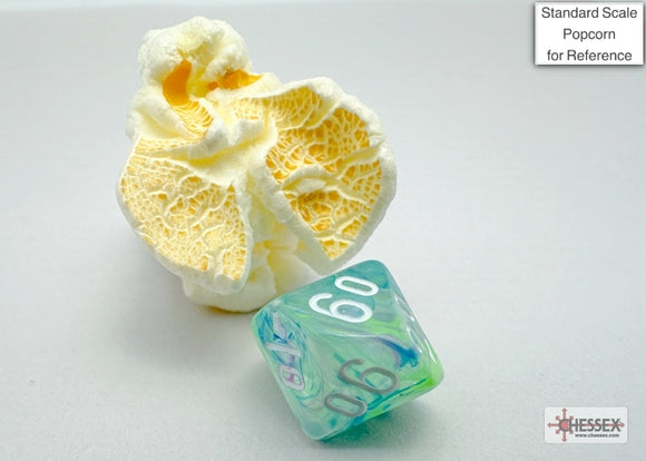 A close-up image of a Festive mini poly waterlily dice by Chessex, showcasing its vibrant colors and intricate design. Beside it is a piece of popcorn for scale, emphasizing the dice's size. The dice features numbers in a clear white font against a swirling green and blue background, making it a beautiful addition to any game.