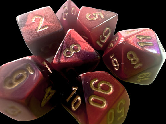 A collection of seven purple-red and gold Mini Gemini RPG dice displayed together. The dice feature various shapes including d4, d6, d8, d10, d12, d20, with clear metallic numbers highlighted in gold for easy readability. The vibrant color blend adds an eye-catching appeal, perfect for tabletop gaming enthusiasts.