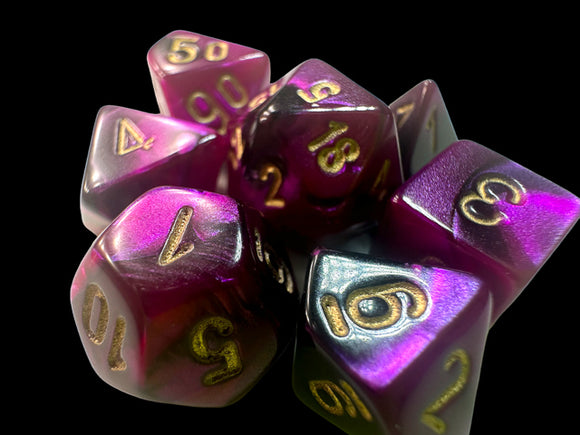 A collection of Mini Gemini RPG Dice in a striking black, purple, and gold color scheme. The dice exhibit sparkling translucent hues, with gold numbers prominently displayed on each face. This set includes a variety of polyhedral dice, perfect for tabletop role-playing games.