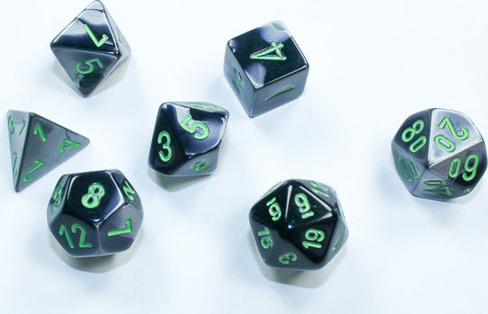A set of Mini Gemini RPG dice in black and grey with green numbers, featuring a d4, d6, d8, d10, d12, and d20, ideal for tabletop gaming.