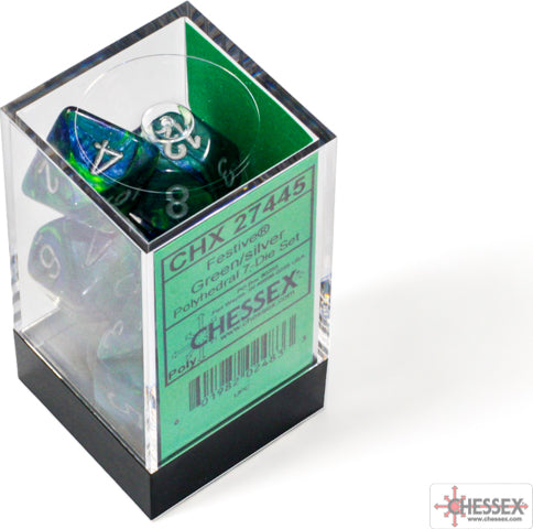 A clear acrylic container holding a set of festive green and silver polyhedral dice from Chessex. The dice are displayed with various numbers visible, showcasing their vibrant color blend.