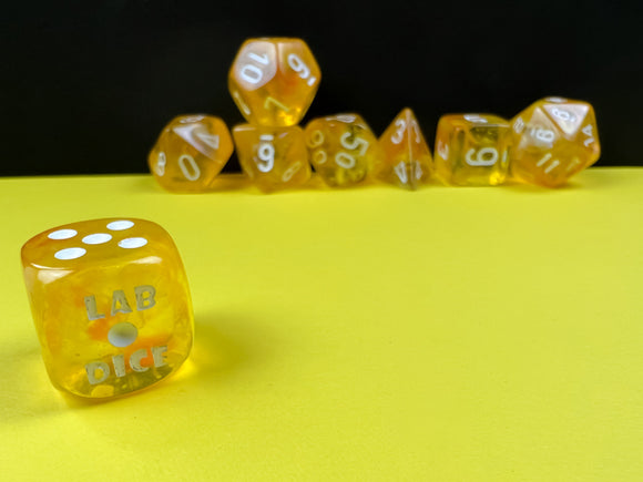 A colorful set of Borealis Canary and White luminary polyhedral dice by Chessex, displayed on a bright yellow surface. The dice feature a transparent canary color with white numbering, showcasing different shaped dice including a cube and an octahedron. The foreground highlights a die with 'LAB DICE' engraved on it, adding a unique touch to this gaming accessory.