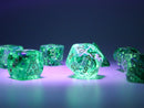 A vibrant 7 piece dice set by Chessex, featuring Borealis Kelp and light green luminary color. The dice are translucent with intricate designs, including numbers and a laboratory flask symbol. Illuminated under purple light, the set showcases a whimsical glow, perfect for tabletop gaming enthusiasts.