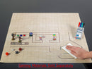 Double-Sided Battlemat by Chessex laid out on a flat surface. The mat features a grid pattern with illustrations including game tokens, dice, and a person wiping the surface. Additional gaming materials like markers are visible in the background, emphasizing its use for tabletop gaming. Note: Gaming materials sold separately.