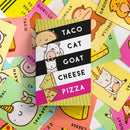 The brightly colored game box for 'Taco Cat Goat Cheese Pizza' by Dolphin Hat Games is surrounded by playful illustrated cards featuring tacos, cats, goats, cheese, and other whimsical characters. The box is predominantly black and white with colorful accents, showcasing a fun and family-friendly design.