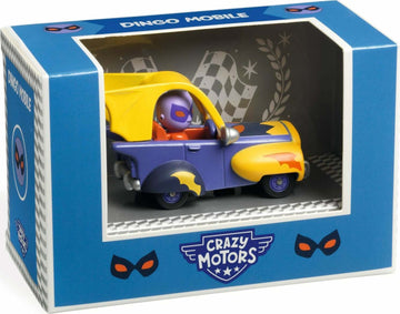 The Crazy Motors: Dingo Mobile toy features a colorful design with purple and yellow accents. The miniature car is nestled within a transparent display box adorned with the Crazy Motors logo and playful mask graphics. A small character, dressed in a mask, is seated in the driver's position, ready for imaginative adventures. The background includes a checkered pattern, evoking a racing theme.