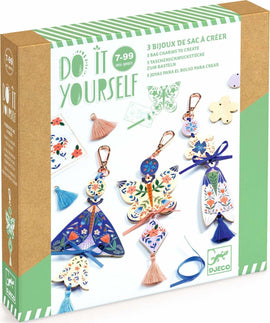 A DIY kit featuring Butterfly Bag Charms by DJECO, displaying three beautifully designed bag charms. Each charm has floral patterns and colorful tassels, perfect for personalizing bags or accessories. The packaging highlights the kit's creative potential with vibrant images and a playful design.