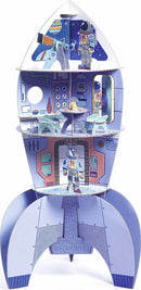 A colorful Space Rocket DIY kit designed by DJECO. The rocket features multiple levels with detailed illustrations of astronauts, a control room, and cozy seating. Ideal for imaginative play and creativity.