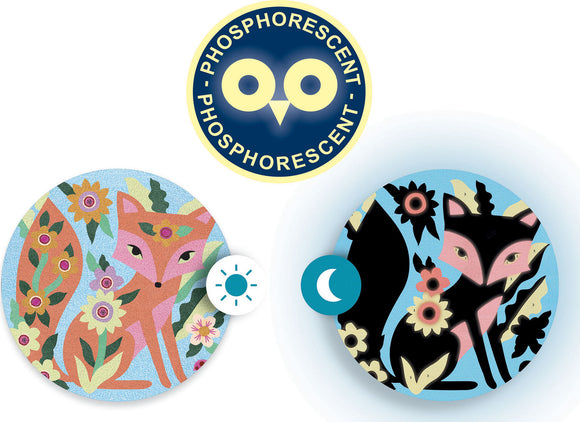 A set of garden lights featuring phosphorescent colored sands. The design showcases two circular patterns: one with a stylized fox surrounded by flowers in pastel colors, and the other with a night version of the fox in darker tones, set against a blue background. Both circular lights are vibrant and eye-catching, ideal for outdoor decoration.