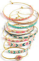 A collection of brightly colored DIY bracelets made from tiny beads, featuring intricate patterns and braided gold strings. The bracelets are displayed in a stacked arrangement, showcasing various colors including pinks, blues, and gold accents, ideal for creative play and crafting.