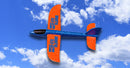 Vibrant X-14 Glider with Hand Launcher in mid-flight against a blue sky dotted with fluffy white clouds. The glider features bright orange wings and a blue body, designed for easy launching and fun outdoor play.