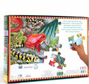 The back of the Love of Amphibians 100-piece jigsaw puzzle by Eeboo features colorful illustrations of various amphibians including frogs, salamanders, and newts. The design highlights vibrant colors with a hand holding a puzzle piece being placed into the image. Informative text describes the life cycle and characteristics of these amphibians.