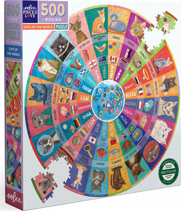 The Cats of the World Round puzzle by Eeboo features a vibrant circle of illustrated cats from various breeds. It is a 500-piece jigsaw puzzle with colorful sections, each representing a different cat breed alongside flags and names from around the world. The packaging showcases the puzzle design and highlights its commitment to recycled materials.