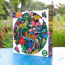 The Jaguars and Butterflies 500-piece jigsaw puzzle by Eeboo features a vibrant circular design with colorful illustrations of jaguars, butterflies, and a variety of flowers. The box is set against a natural background, highlighting the intricate artwork and eco-friendly packaging.