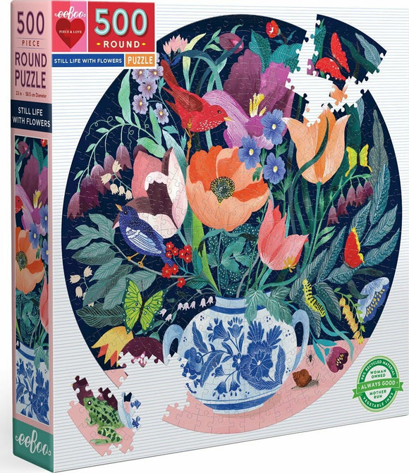 Eeboo Still Life with Flowers jigsaw puzzle featuring a vibrant, round 500-piece design. The puzzle showcases a beautifully illustrated floral arrangement in a decorative vase, surrounded by colorful birds and insects, set against a deep navy background.