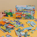 A vibrant 20-piece jigsaw puzzle featuring various vehicles, displayed on a yellow surface. A child's hand holds a puzzle piece with colorful illustrations. The puzzle box shows a lively scene with different modes of transportation, including cars, trucks, and airplanes.