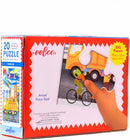 The Eeboo Vehicles 20 Piece Puzzle features colorful illustrations of various vehicles, including a bicycle, a truck, and children engaging with them. The puzzle box prominently displays the title and emphasizes that it measures 11 inches by 15 inches. A hand is shown fitting a piece into the puzzle, showcasing the actual piece size.