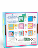 The back of the Eeboo Outdoors Scavenger Hunt Game box, showcasing game components and illustrated guides. Elements include various objects and categories like 'color', 'size', 'senses', 'shapes', and 'materials' aimed at engaging children's observational skills in nature. Brightly colored visuals promote playful learning and exploration.