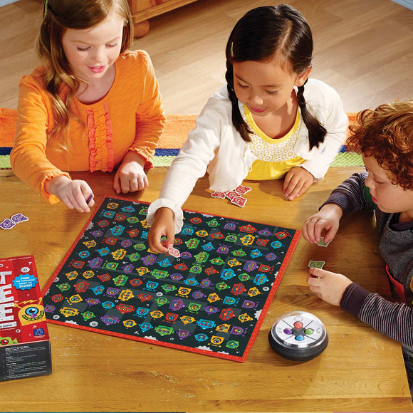 Three children playing Robot Face Race game by Educational Insights. The brightly colored game board features various robot faces, and children are placing tokens on the board while engaging in the game.