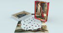 The Accolade jigsaw puzzle by Edmund Blair Leighton, designed by Eurographics. The image shows the puzzle box next to an incomplete puzzle depicting a knight kneeling before a lady in medieval attire, surrounded by onlookers. The puzzle consists of colorful pieces arranged on a flat surface with some scattered pieces in the box.