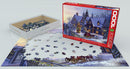 A jigsaw puzzle titled 'Home for the Holidays' by Dominic Davison, featuring a picturesque snowy scene of a house decorated for Christmas with a tree and carriage. The box is shown alongside scattered puzzle pieces on a partially completed puzzle.