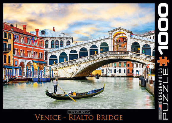 Eurographics jigsaw puzzle featuring the iconic Rialto Bridge in Venice. The art depicts a scenic view with colorful buildings along the Grand Canal, a gondolier navigating the waters, and a beautiful sky at sunset. Ideal for puzzle enthusiasts and lovers of Venice's architectural beauty.
